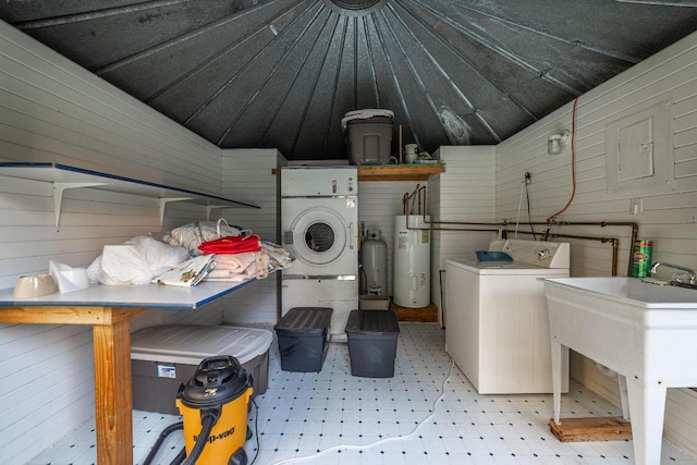 laundry area featuring wooden walls, electric water heater, washer / dryer, and light tile floors