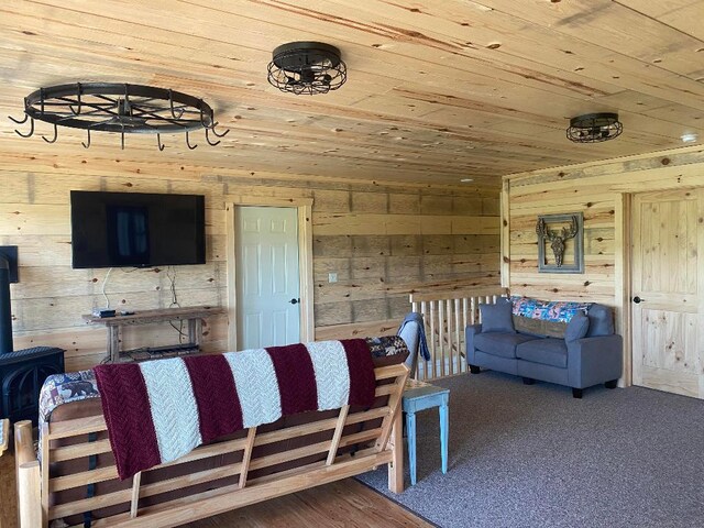 carpeted living room featuring wood ceiling, wood walls, and a wood stove