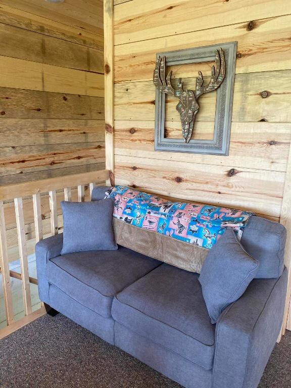 carpeted living room featuring wood walls