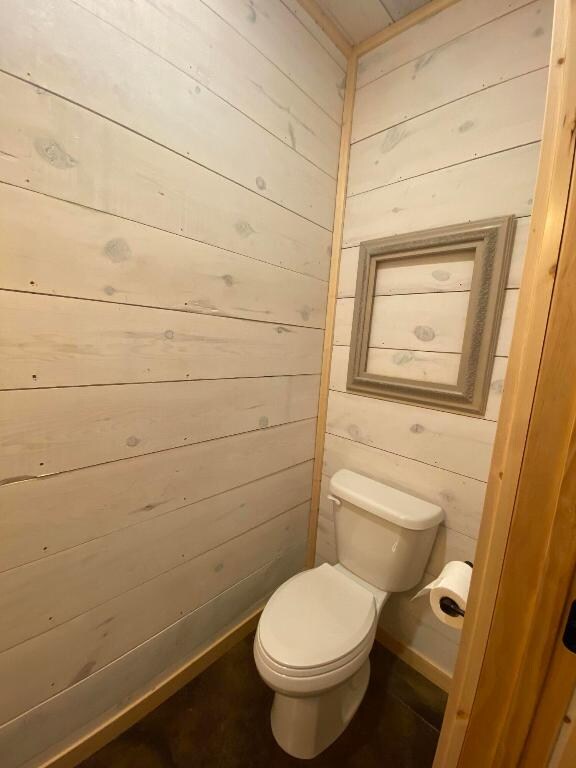 bathroom with toilet and wood walls