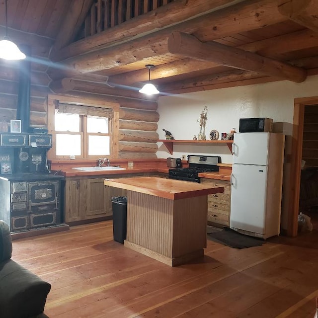 kitchen featuring white fridge, rustic walls, decorative light fixtures, wooden counters, and gas stove