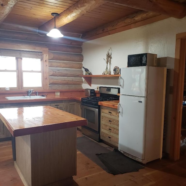 kitchen with white refrigerator, stainless steel range with gas stovetop, sink, wood ceiling, and rustic walls