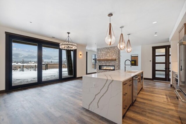 kitchen with sink, decorative light fixtures, stainless steel dishwasher, and light stone countertops