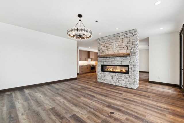 unfurnished living room with dark hardwood / wood-style flooring and a stone fireplace