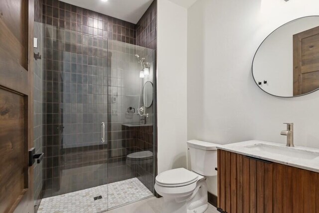 bathroom featuring toilet, tile patterned flooring, a shower with shower door, and vanity