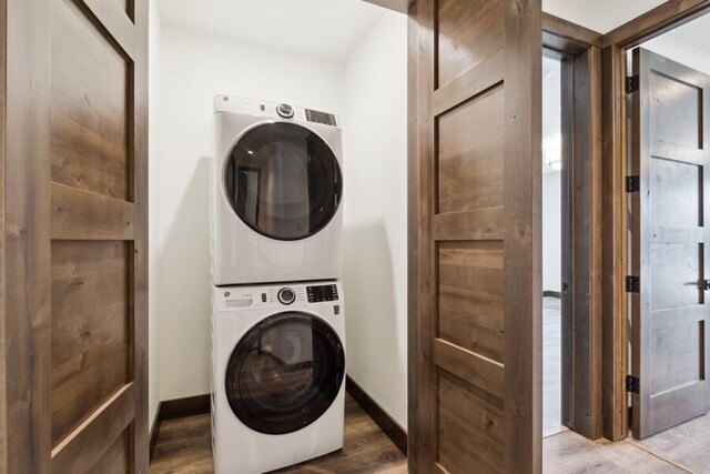 clothes washing area featuring stacked washer / drying machine and hardwood / wood-style floors