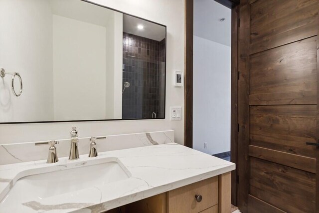 bathroom featuring tiled shower and vanity