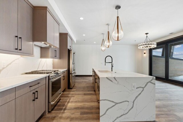 kitchen featuring appliances with stainless steel finishes, hanging light fixtures, light stone countertops, dark wood-type flooring, and tasteful backsplash