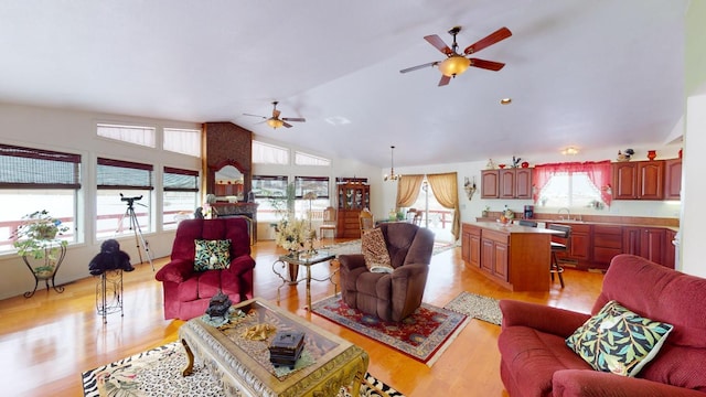 living room featuring vaulted ceiling, light hardwood / wood-style flooring, and ceiling fan with notable chandelier