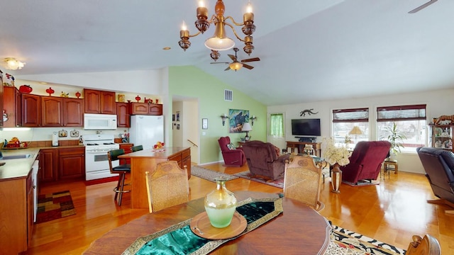 dining space with light hardwood / wood-style floors, high vaulted ceiling, sink, and ceiling fan with notable chandelier