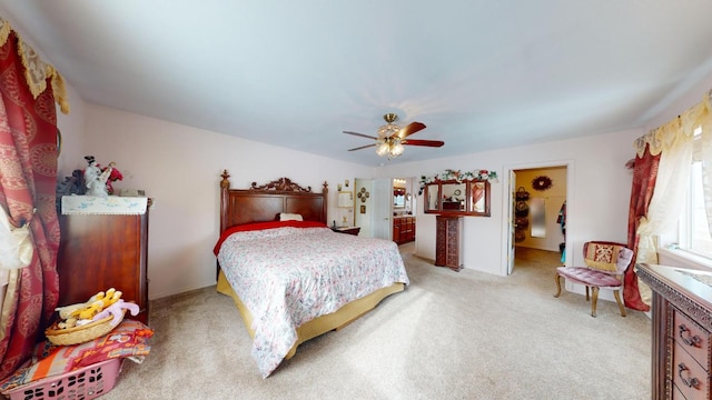 carpeted bedroom with ceiling fan, a spacious closet, and ensuite bath