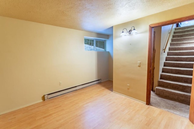 interior space with light hardwood / wood-style flooring, a baseboard heating unit, and a textured ceiling