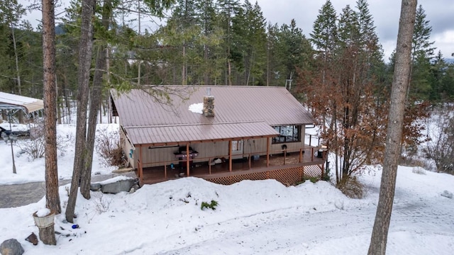 snow covered back of property featuring a wooden deck