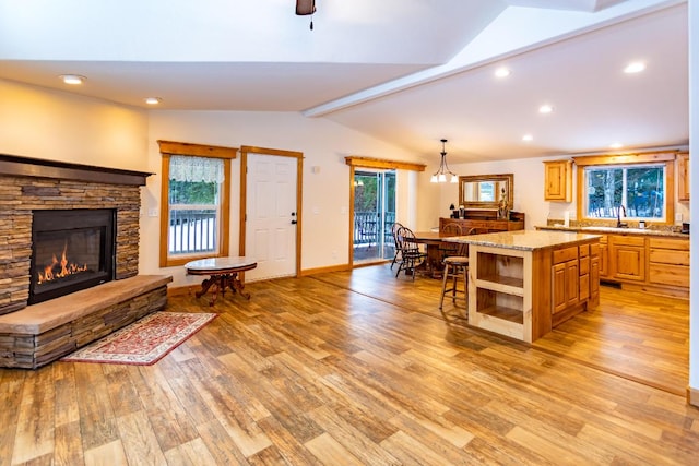 kitchen with plenty of natural light, light hardwood / wood-style floors, light stone countertops, and a center island