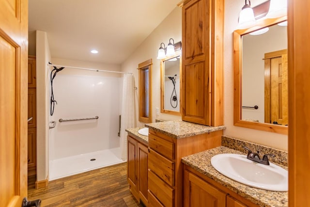 bathroom featuring a shower, wood-type flooring, and vanity with extensive cabinet space