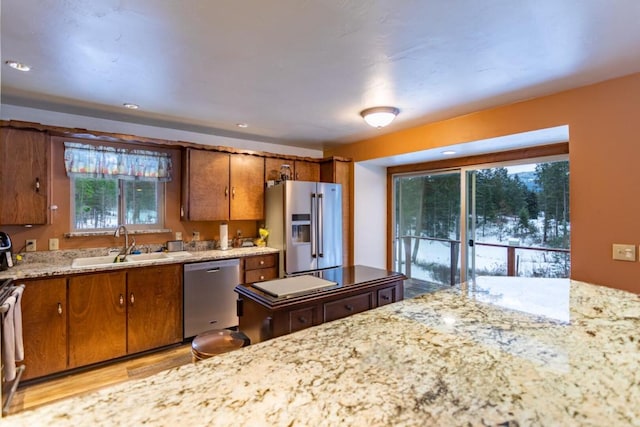 kitchen featuring light stone counters, light hardwood / wood-style flooring, sink, and stainless steel appliances