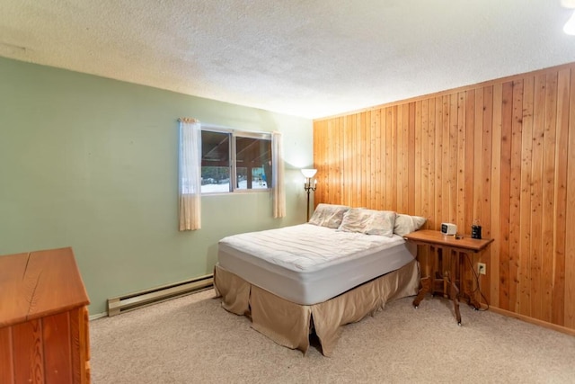 carpeted bedroom with baseboard heating, wood walls, and a textured ceiling