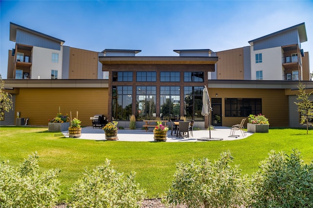 rear view of house with a lawn, a balcony, and a patio area