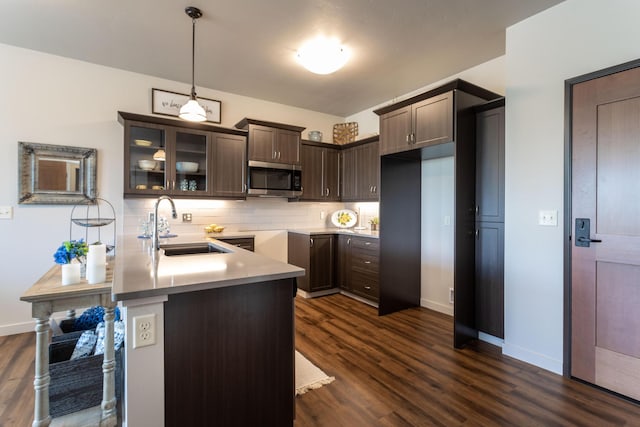 kitchen featuring backsplash, dark brown cabinets, decorative light fixtures, kitchen peninsula, and dark hardwood / wood-style floors