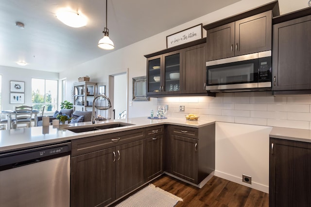 kitchen with hanging light fixtures, sink, dark brown cabinets, dark wood-type flooring, and appliances with stainless steel finishes