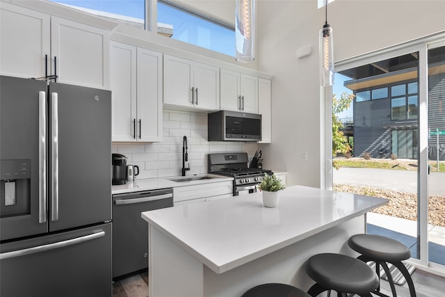 kitchen with dark hardwood / wood-style flooring, stainless steel appliances, tasteful backsplash, and white cabinetry