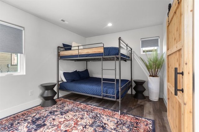 bedroom with a barn door and dark wood-type flooring