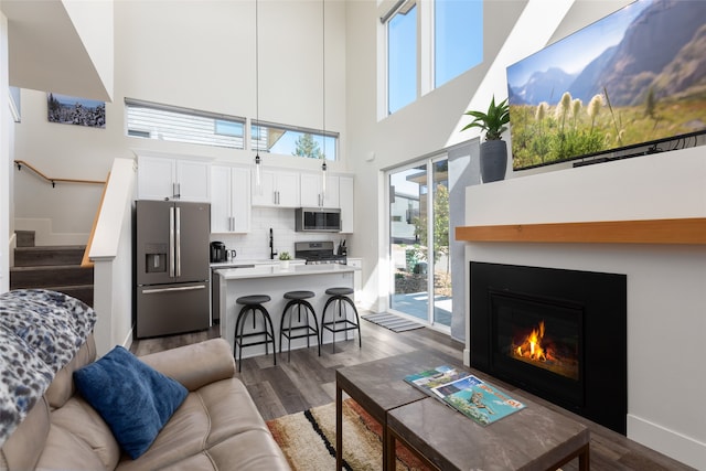 living room featuring a towering ceiling, dark hardwood / wood-style floors, and sink