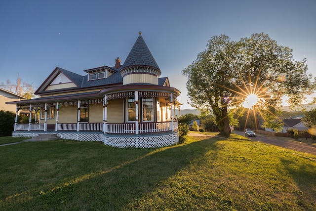 back house at dusk with a lawn and a porch