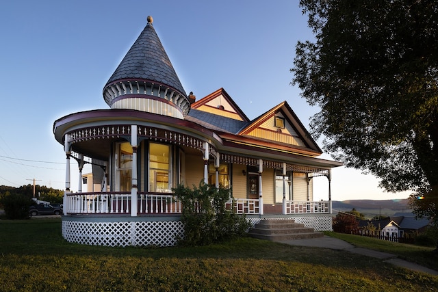 victorian house featuring covered porch and a yard