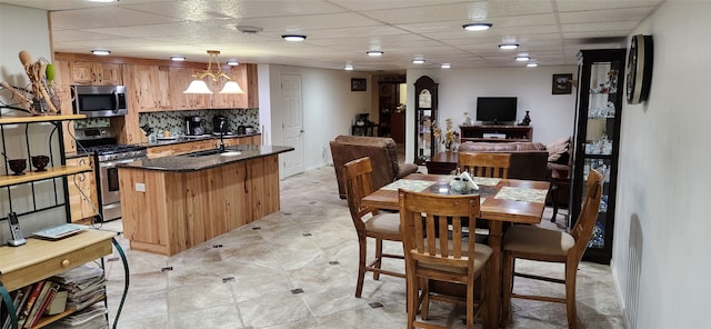 tiled dining area with a drop ceiling, sink, and a chandelier