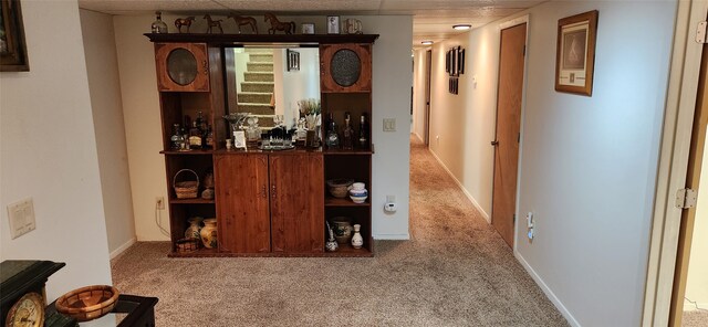 hallway with carpet floors and a paneled ceiling