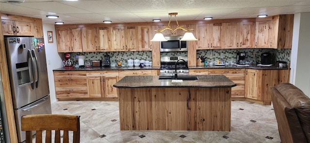 kitchen featuring appliances with stainless steel finishes, pendant lighting, a drop ceiling, light tile floors, and a kitchen island with sink