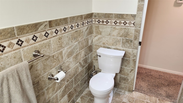 bathroom with tile flooring, toilet, and tile walls