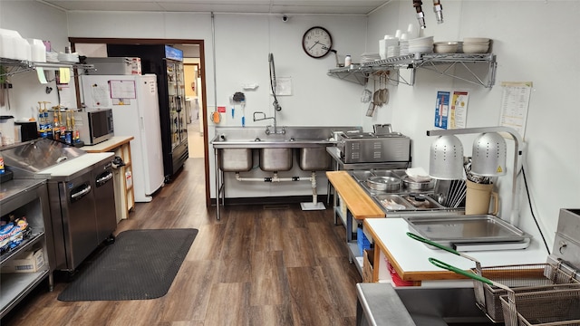 kitchen with white fridge, stainless steel counters, and dark wood-type flooring