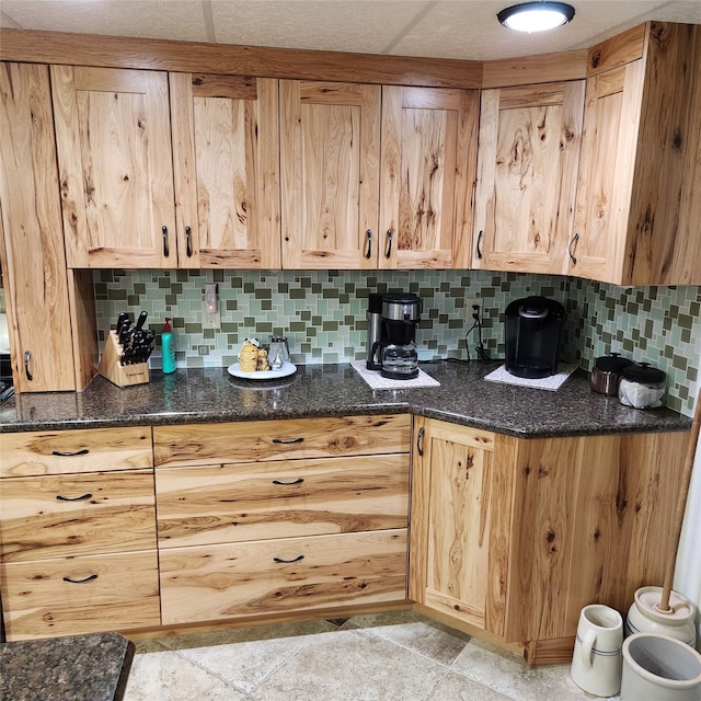 kitchen with dark stone counters, backsplash, and light tile floors