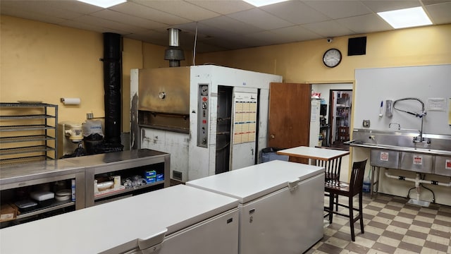 kitchen featuring a drop ceiling, fridge, white cabinets, and light tile floors