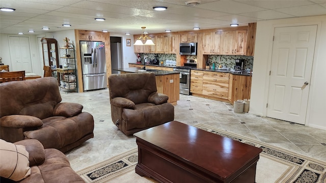 living room with a paneled ceiling, sink, and light tile floors