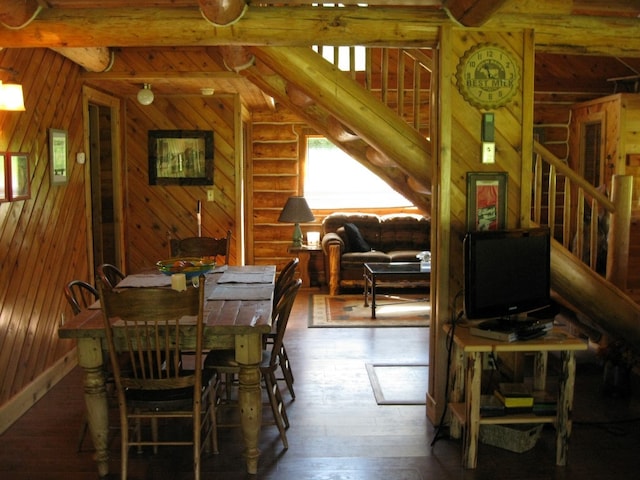 dining room featuring wooden walls, log walls, and hardwood / wood-style flooring