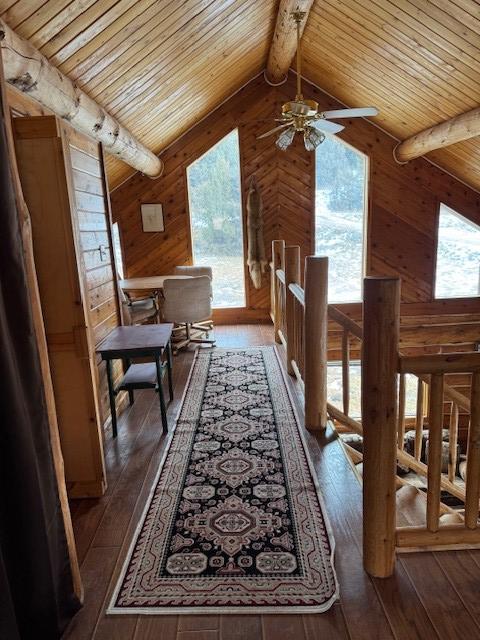 hallway with wooden walls, dark hardwood / wood-style flooring, beamed ceiling, and wood ceiling