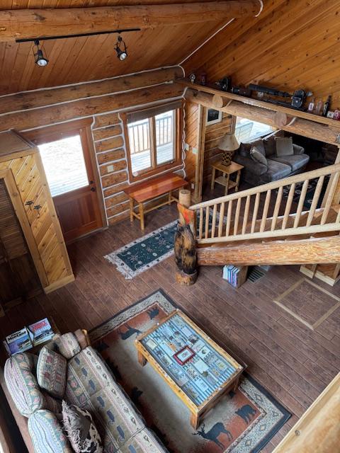 interior space featuring hardwood / wood-style floors, wooden ceiling, log walls, and track lighting