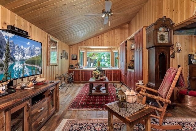 living area featuring hardwood / wood-style floors, wooden ceiling, wooden walls, vaulted ceiling, and ceiling fan