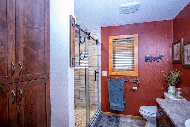 bathroom with an enclosed shower, toilet, a textured ceiling, and vanity