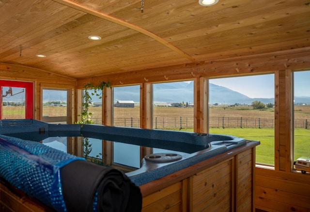 sunroom / solarium with lofted ceiling, wooden ceiling, a hot tub, and a rural view