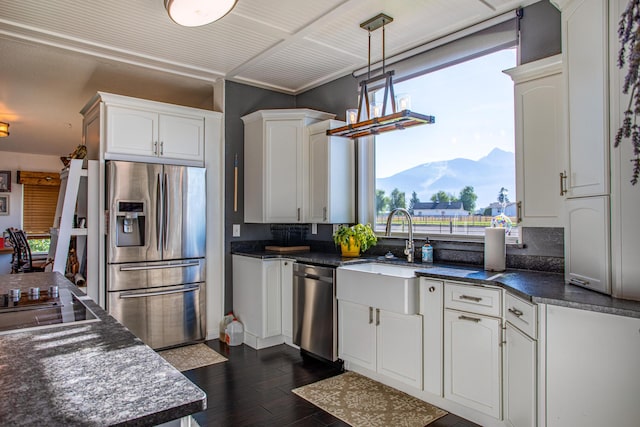 kitchen featuring appliances with stainless steel finishes, backsplash, decorative light fixtures, dark hardwood / wood-style flooring, and white cabinetry