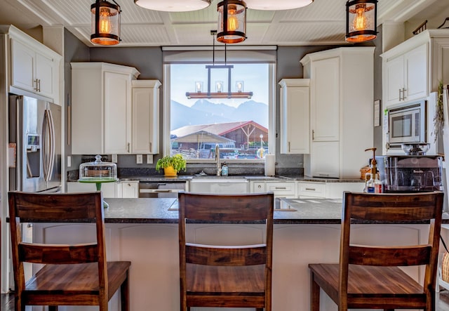 kitchen with white cabinets, a breakfast bar area, hanging light fixtures, and appliances with stainless steel finishes