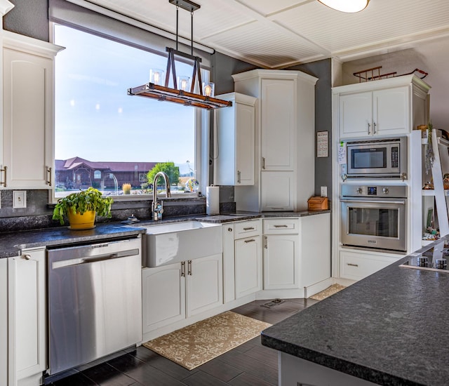 kitchen with appliances with stainless steel finishes, pendant lighting, tasteful backsplash, and white cabinets