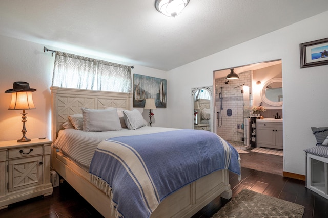 bedroom featuring dark hardwood / wood-style flooring, brick wall, ensuite bath, lofted ceiling, and sink