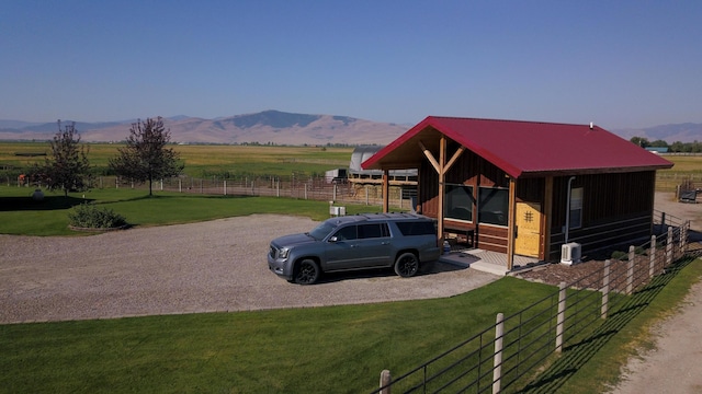 view of front of house featuring a mountain view, a rural view, and a front lawn