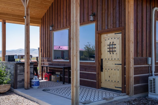 view of exterior entry with a mountain view and central air condition unit