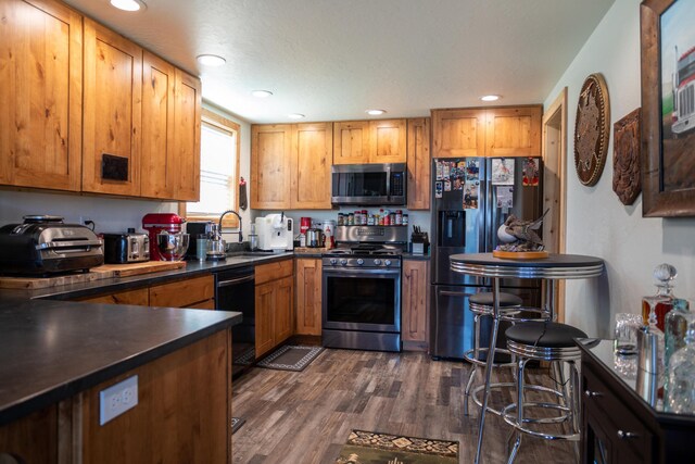 kitchen featuring a breakfast bar area, sink, dark wood-type flooring, and black appliances